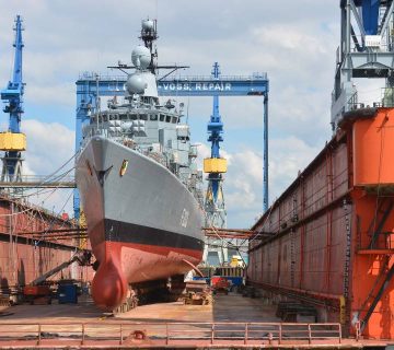 تصویر بدنه یک کشتی بزرگ در حال پاک‌سازی و آماده‌سازی سطح با استفاده از گریت مسباره برای رنگ‌آمیزی مجدد